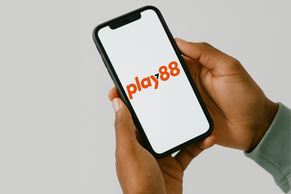 Person holding a smartphone displaying the Play88 logo on a white screen.